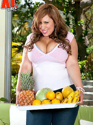 BBW Gya carries a tray of fruit over to a sofa before stripping naked