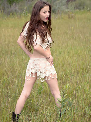 Skinny young girl Iva Nora teases her long hair in a field