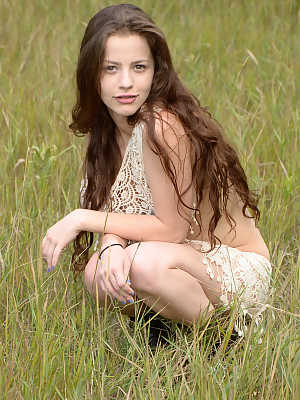 Skinny young girl Iva Nora teases her long hair in a field