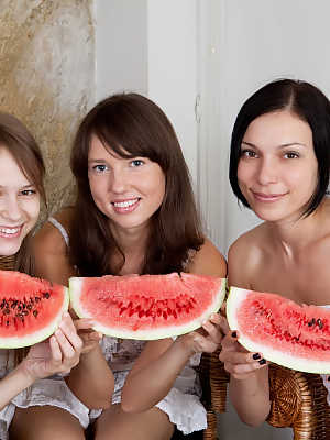 Three young girls cover their naked body in seeds while eating a watermelon