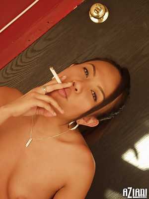 Brunette Asian girl Jade Marcela smokes a cigarette while stripping