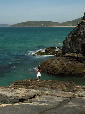 Asian teen makes her nude modelling debut as the surf pounds the coast below