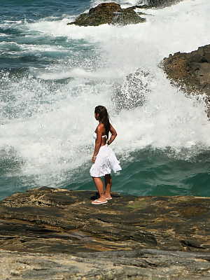 Asian teen makes her nude modelling debut as the surf pounds the coast below