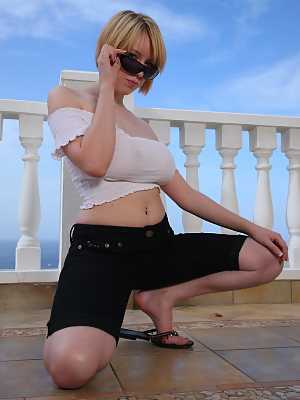 Busty MILF in sunglasses Jenny Jones toys her shaved clam on a balcony